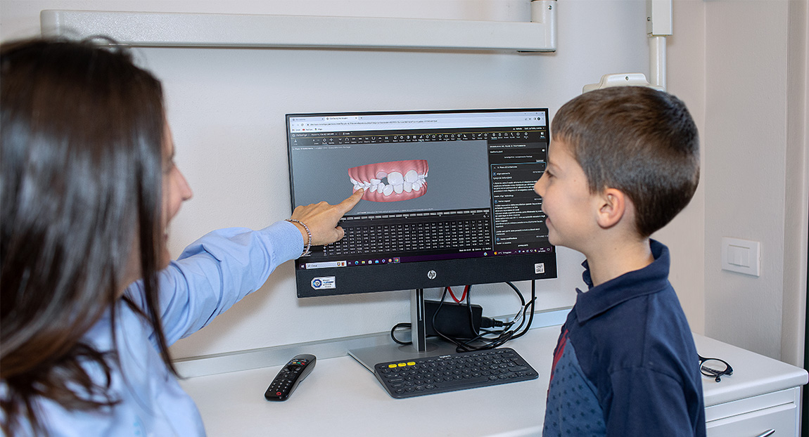 Dentista mostra il disegno di una dentatura sullo schermo di un pc. Ortodonzia bambino studio dentistico brescia